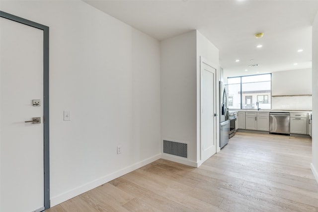 interior space featuring light wood-type flooring, appliances with stainless steel finishes, gray cabinetry, and sink