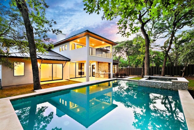 pool at dusk with an in ground hot tub and a patio