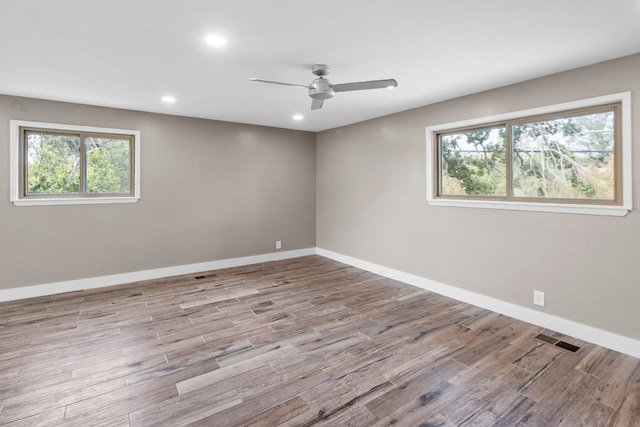 spare room featuring plenty of natural light, ceiling fan, and hardwood / wood-style flooring