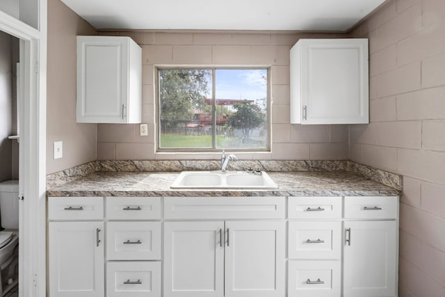 kitchen featuring sink, tile walls, and white cabinetry