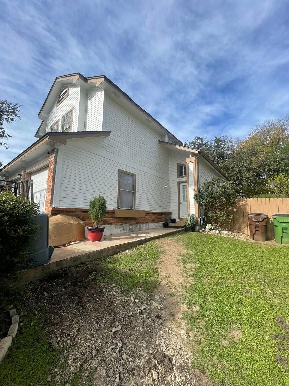 back of house featuring an attached garage, fence, and a lawn