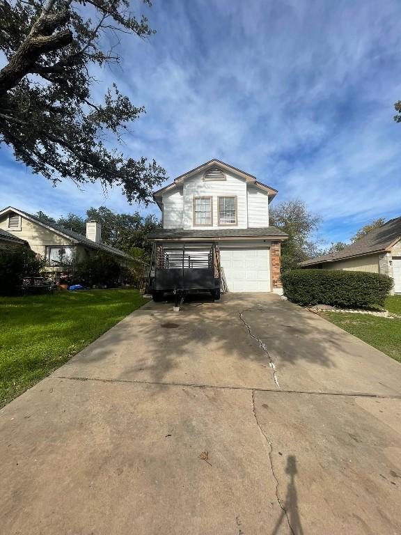 traditional-style home featuring a front lawn, an attached garage, and driveway