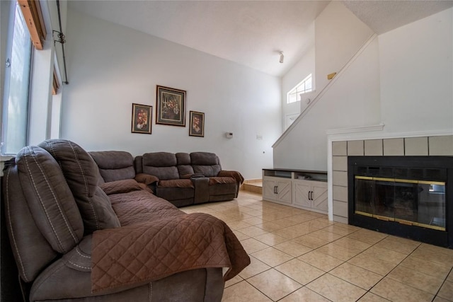 living area featuring a towering ceiling, light tile patterned flooring, and a tiled fireplace