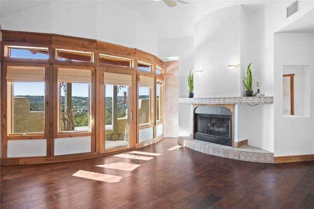 unfurnished living room featuring ceiling fan, hardwood / wood-style flooring, a brick fireplace, and high vaulted ceiling