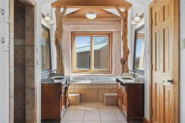 bathroom featuring a wealth of natural light, tiled tub, and vanity