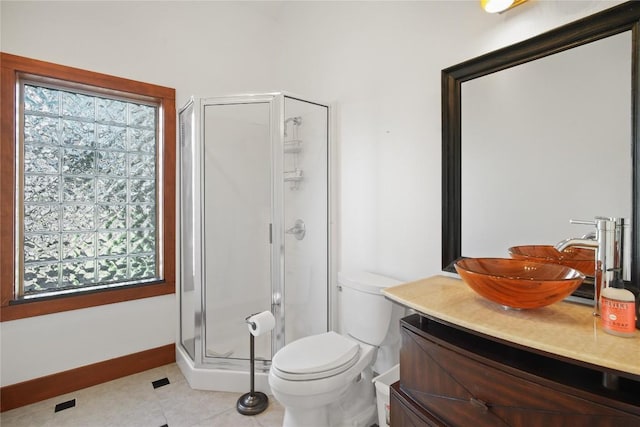 bathroom featuring tile patterned floors, toilet, vanity, and a shower with shower door