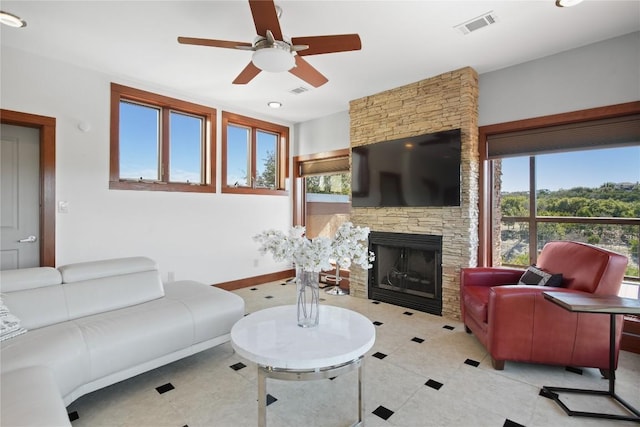 living room with a stone fireplace and ceiling fan