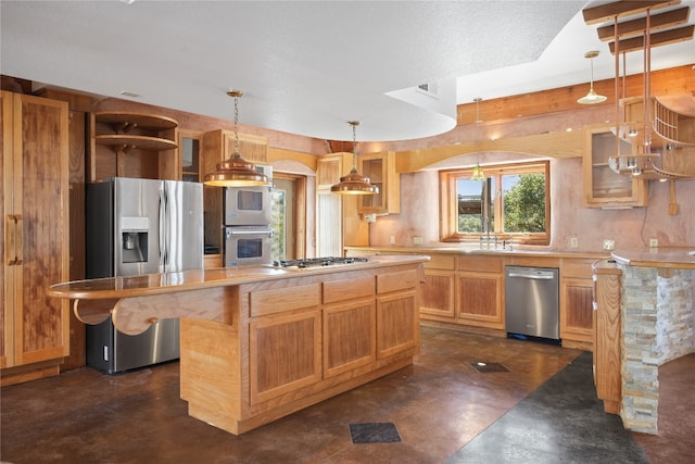 kitchen with sink, stainless steel appliances, pendant lighting, and a kitchen island