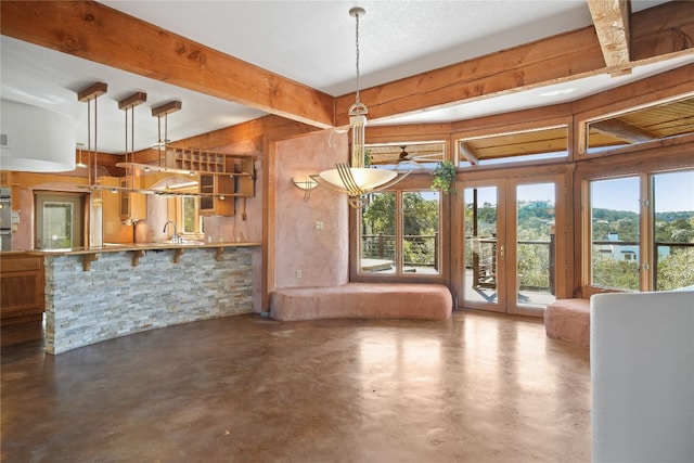 unfurnished living room with sink, beam ceiling, french doors, and concrete flooring