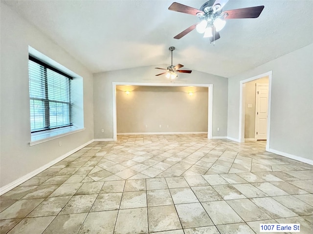 empty room featuring lofted ceiling, light tile floors, and ceiling fan