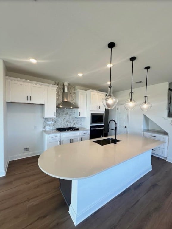 kitchen featuring wall chimney exhaust hood, white cabinetry, a large island, and pendant lighting