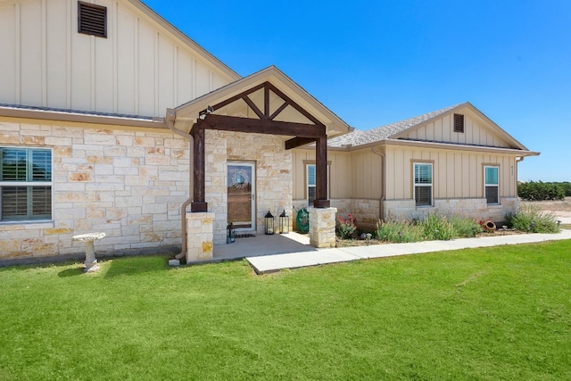 rear view of property with stone siding, a lawn, and board and batten siding