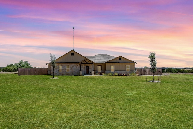 back house at dusk featuring a lawn