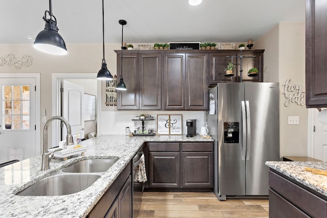 kitchen featuring decorative light fixtures, stainless steel appliances, light wood-style flooring, a sink, and dark brown cabinetry