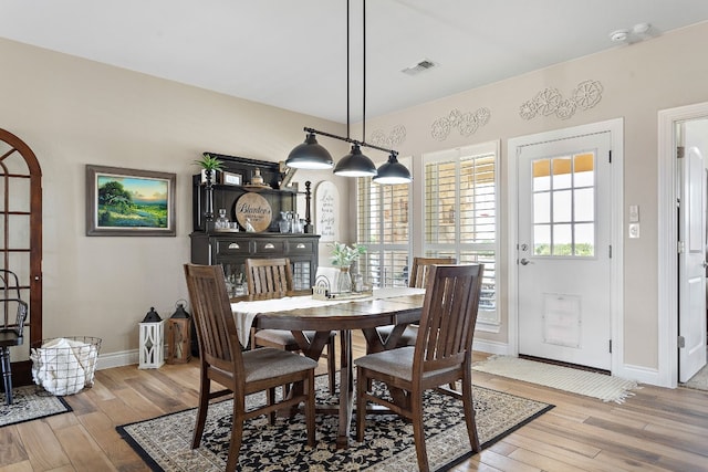 dining space with light wood-style flooring, visible vents, and baseboards