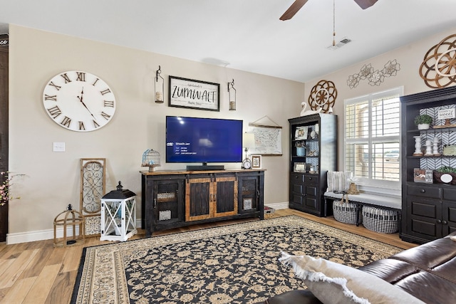 living area featuring visible vents, ceiling fan, baseboards, and wood finished floors