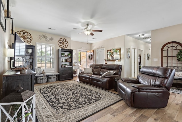 living area with wood finished floors, visible vents, and a ceiling fan