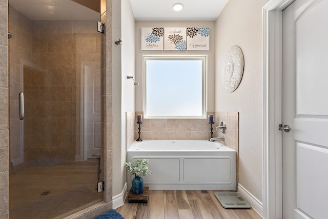 full bathroom featuring a garden tub, a shower stall, baseboards, and wood finished floors