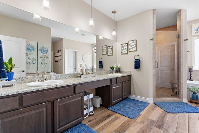 full bath with a sink, a shower stall, and wood finished floors