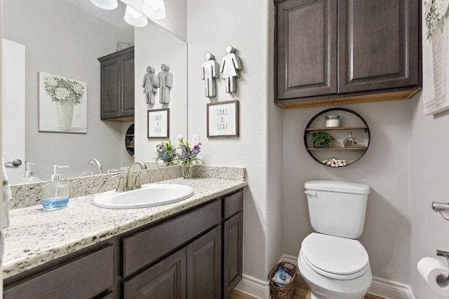 half bath featuring toilet, baseboards, and vanity