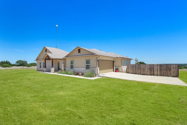 view of front of home featuring concrete driveway, board and batten siding, fence, stone siding, and a front lawn