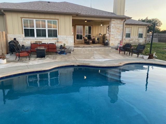 pool at dusk with an outdoor hangout area, a patio area, and a fenced in pool