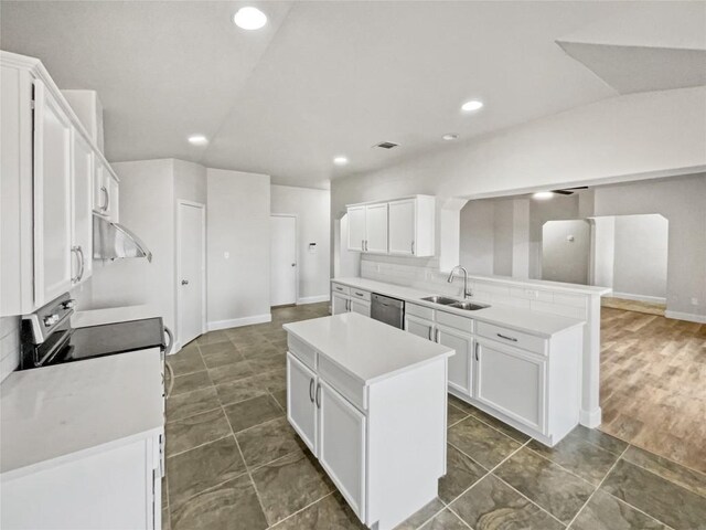 kitchen featuring appliances with stainless steel finishes, sink, white cabinets, backsplash, and a center island