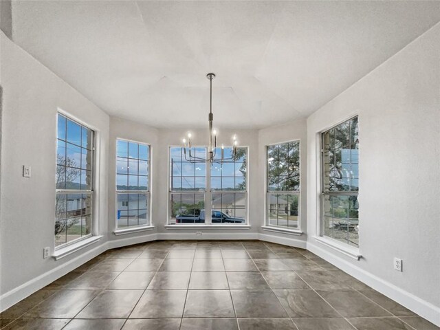 unfurnished dining area featuring dark tile patterned floors and a notable chandelier