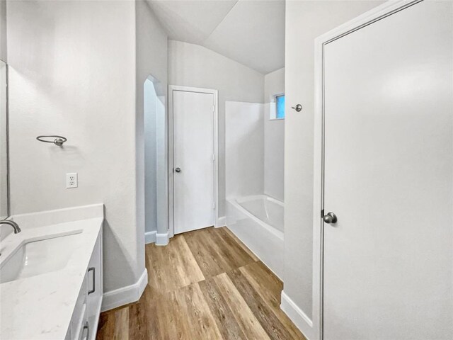 bathroom with vanity, lofted ceiling, hardwood / wood-style floors, and a bathtub