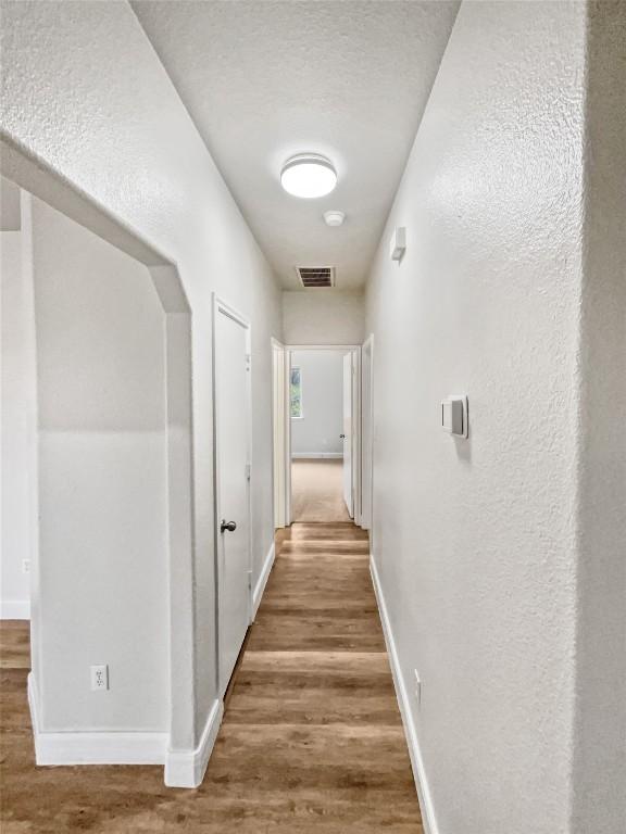 corridor with hardwood / wood-style floors and a textured ceiling