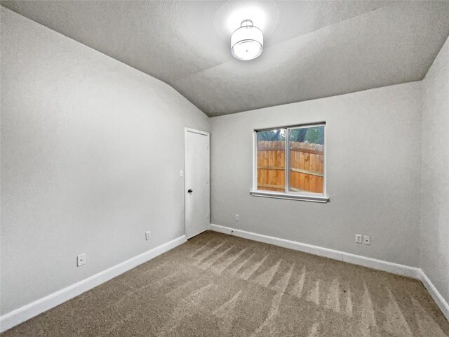 empty room featuring vaulted ceiling and carpet