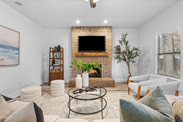 living room featuring a fireplace, wood-type flooring, and brick wall