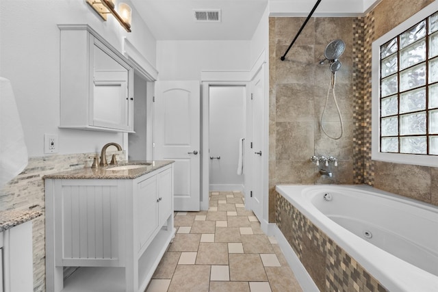 bathroom with tile patterned flooring, tiled shower / bath combo, and vanity