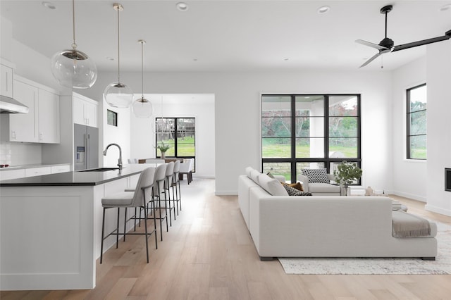 living room featuring ceiling fan, sink, a wealth of natural light, and light hardwood / wood-style flooring