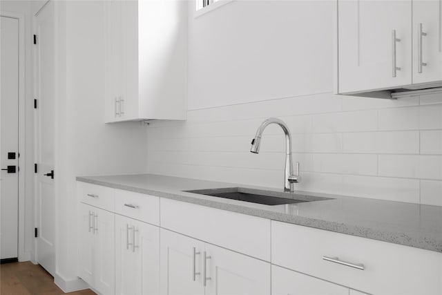 kitchen with dark hardwood / wood-style floors, decorative backsplash, sink, white cabinetry, and light stone countertops