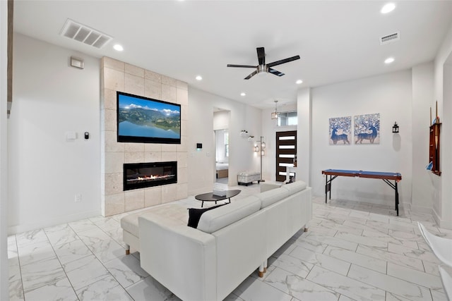 living room featuring ceiling fan, tile walls, a tiled fireplace, and light tile patterned flooring