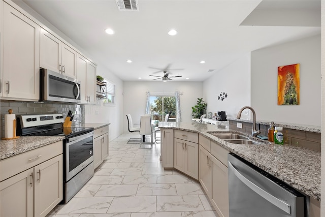 kitchen featuring ceiling fan, light stone countertops, light tile patterned floors, sink, and stainless steel appliances