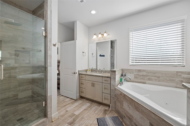 bathroom with hardwood / wood-style flooring, separate shower and tub, and vanity