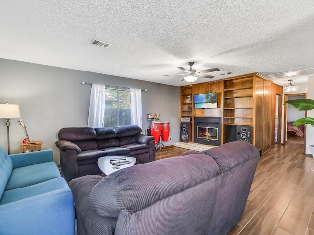 living room with a textured ceiling, hardwood / wood-style flooring, and ceiling fan