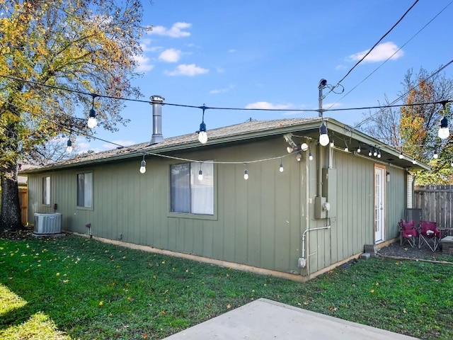 view of side of home featuring cooling unit and a lawn