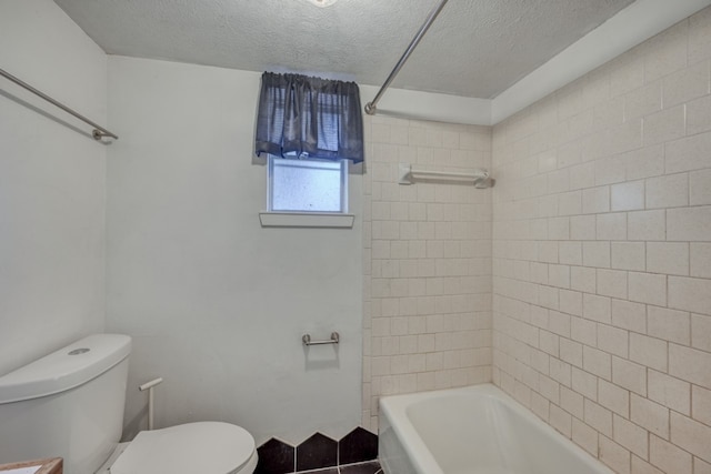 bathroom with tile patterned flooring, a textured ceiling, toilet, and tiled shower / bath