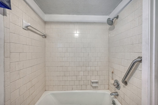 bathroom with a textured ceiling and tiled shower / bath combo