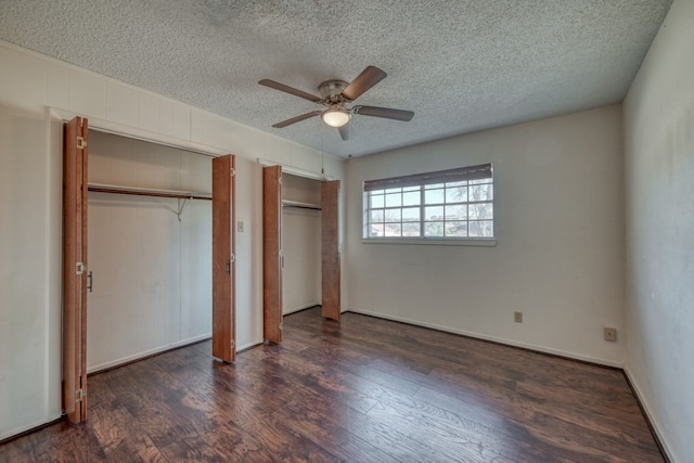 unfurnished bedroom featuring multiple closets, ceiling fan, dark wood-type flooring, and a textured ceiling