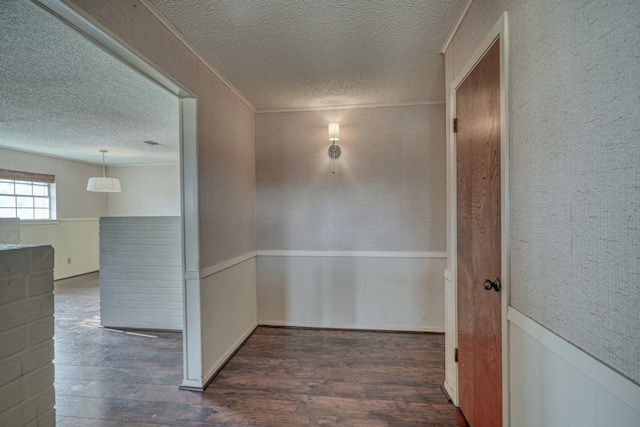 hallway with a textured ceiling, dark hardwood / wood-style flooring, and crown molding