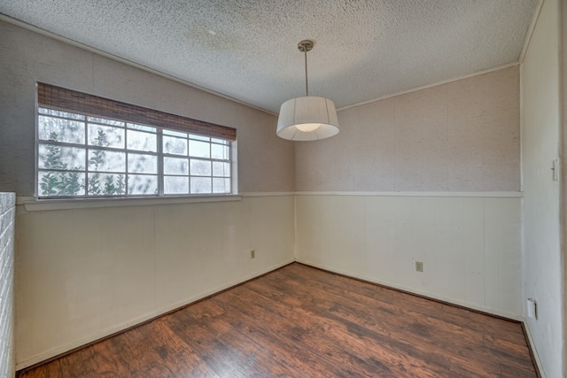 spare room featuring dark hardwood / wood-style floors, crown molding, and a textured ceiling