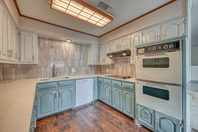 kitchen with sink, dark hardwood / wood-style floors, white appliances, white cabinets, and ornamental molding