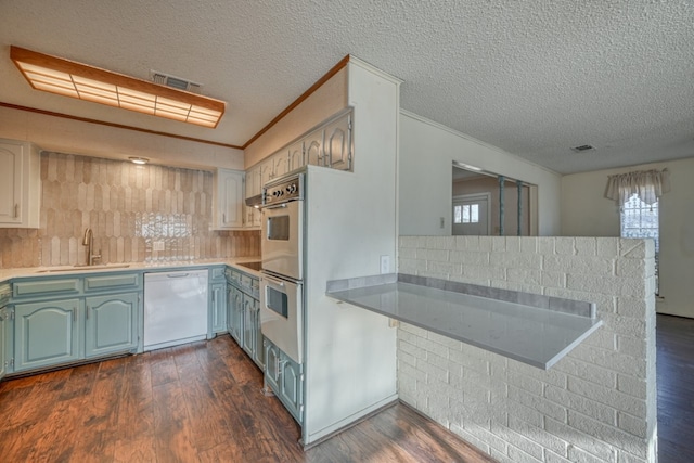 kitchen with dishwasher, backsplash, dark wood-type flooring, sink, and kitchen peninsula