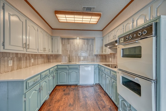 kitchen with white appliances, backsplash, dark wood-type flooring, sink, and ornamental molding