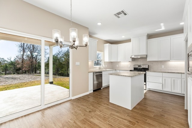 kitchen featuring stainless steel appliances, a notable chandelier, white cabinets, a kitchen island, and hanging light fixtures