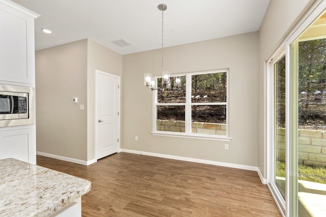 unfurnished dining area with light hardwood / wood-style flooring and an inviting chandelier